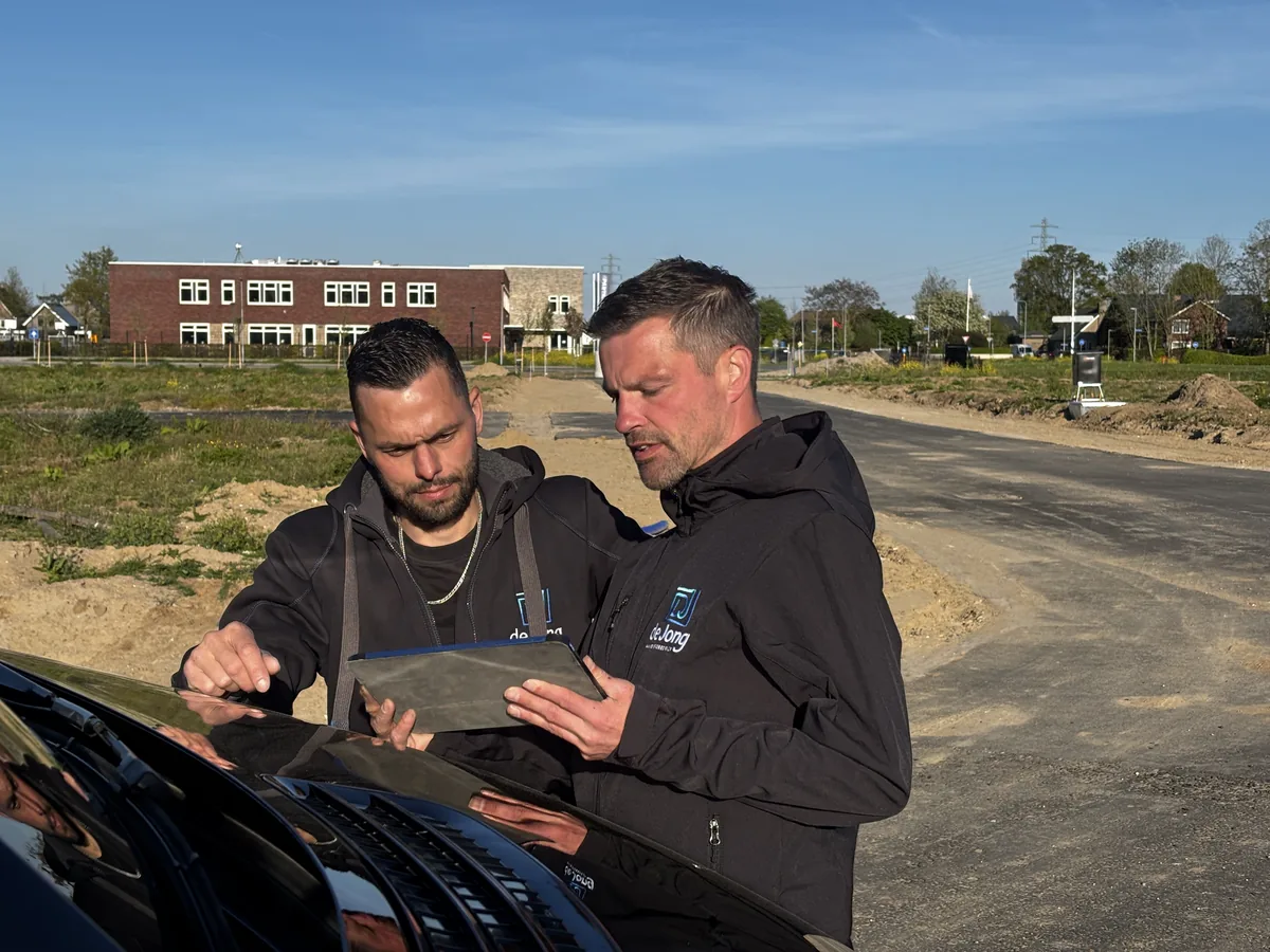 Uitvoerder en bouwvakker van De Jong bespreken de bouwtekening op de tablet